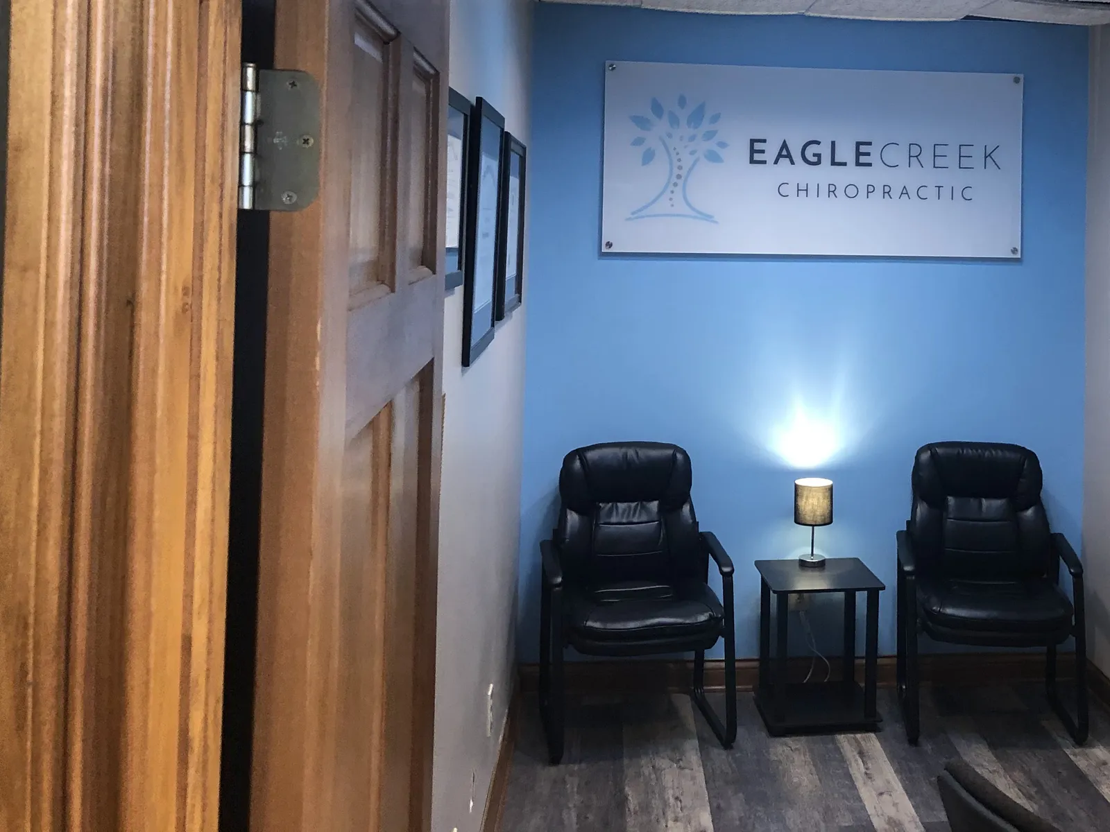 A quiet consultation room at Eagle Creek Chiropractic with two chairs beneath the practice sign.