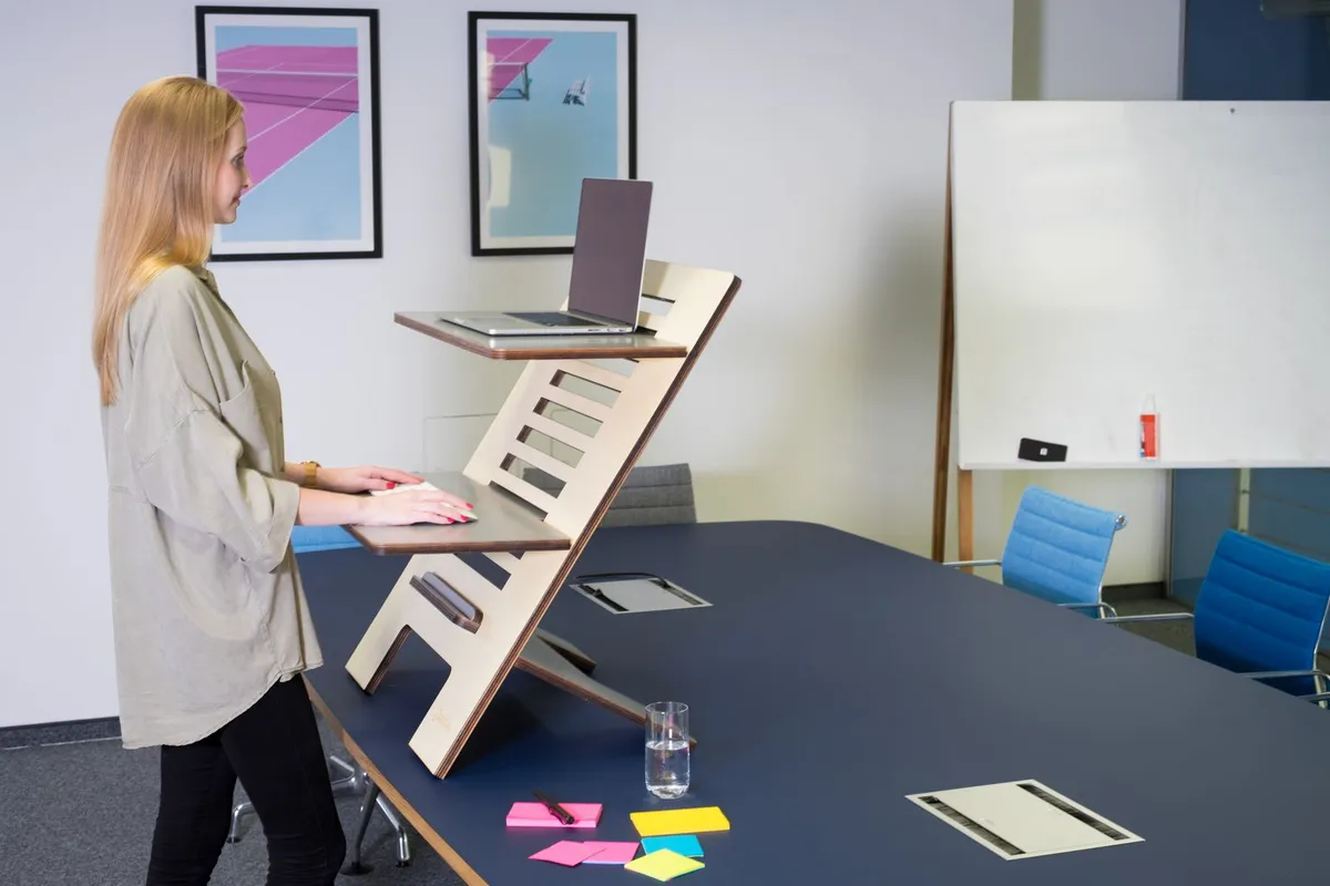 A person works at an ergonomic standing desk in a bright modern office.